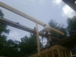 Carpenter setting a ridge beam over a new addition frame — Ice Dam Removal by Roofing Brothers in North Garden