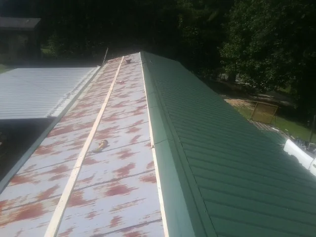 Old rusted panels beside newly installed green metal roofing — Wind Damage Roof Repair by Roofing Brothers in North Garden