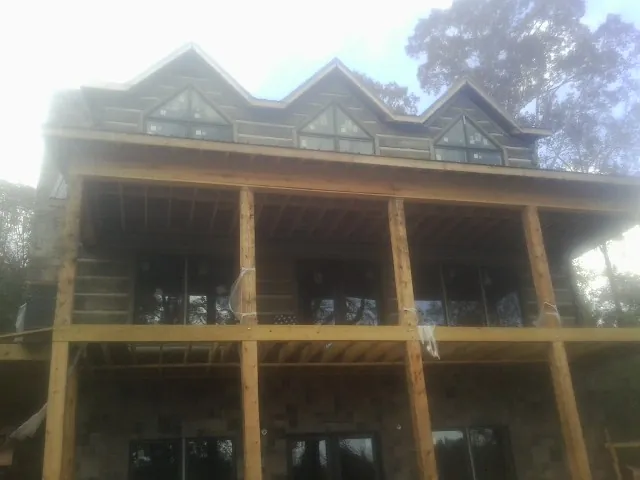 Dormers and porch framing on a large log home under construction — Roof Coating work by our crew in North Garden