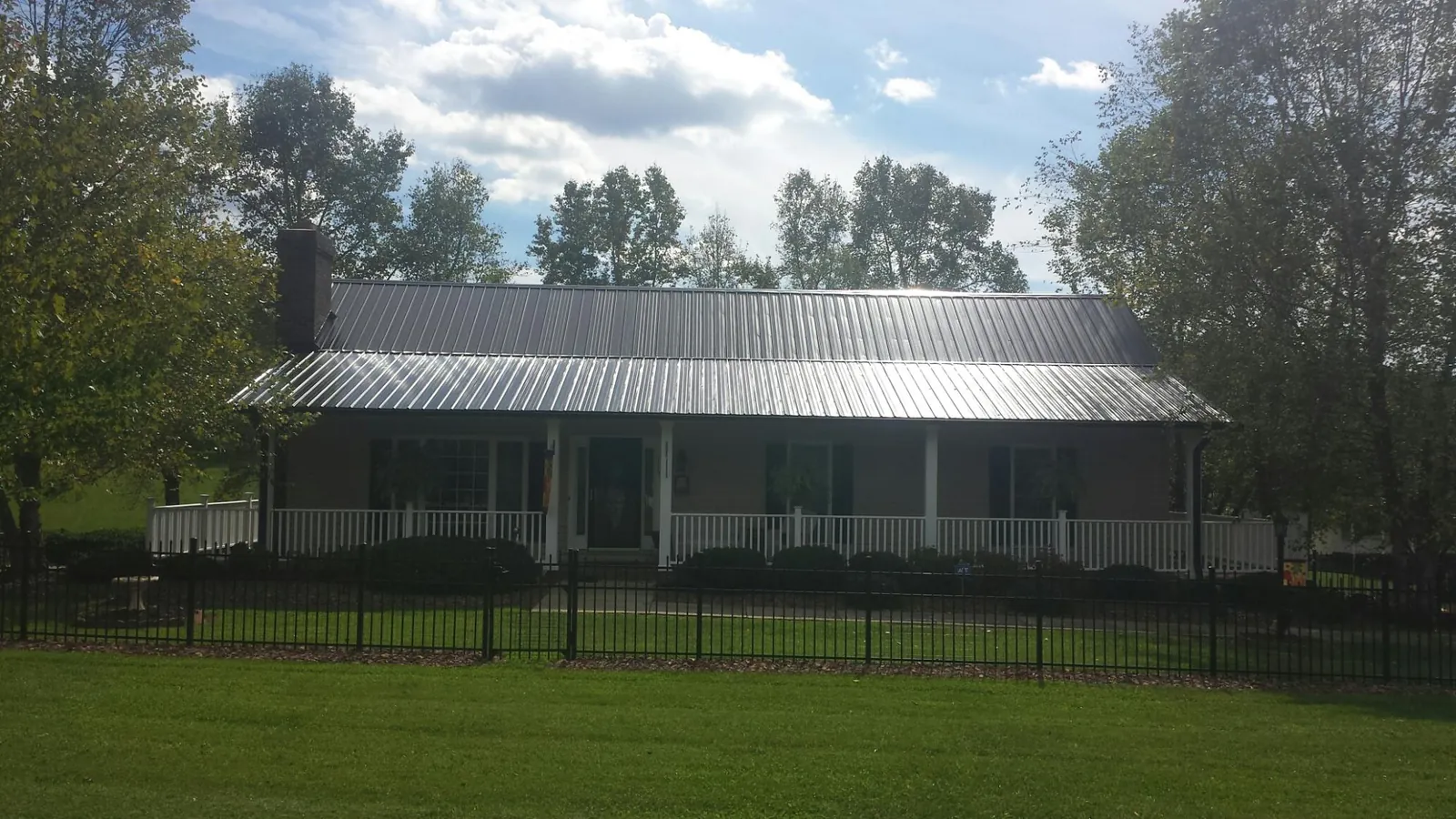 Gray metal roof on a brick ranch with a full width front porch in North Garden