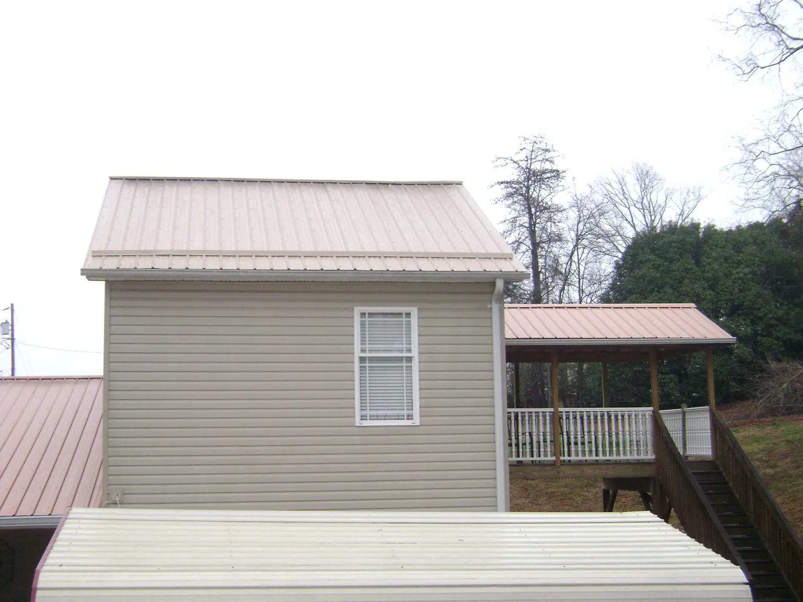Tan metal roofs on a two story addition and attached porch, from a Roof Replacement job in North Garden