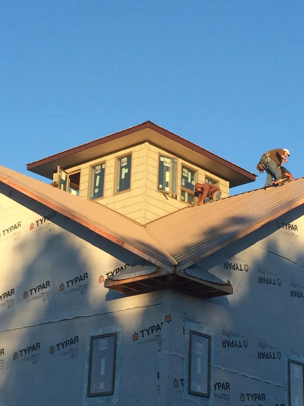 Roofers working around a rooftop cupola on a new metal roof at sunset — Roof Waterproofing in North Garden by Roofing Brothers